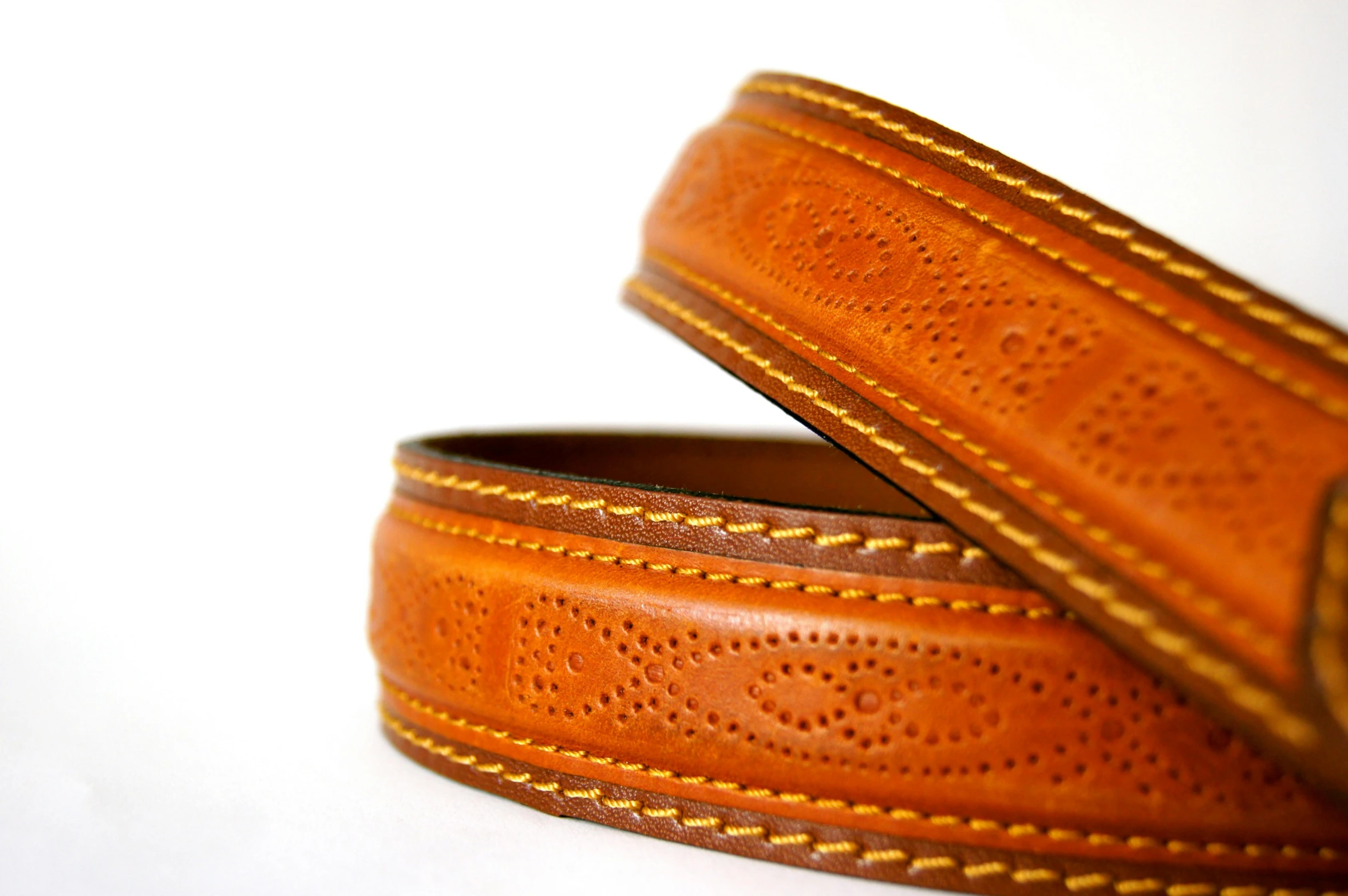 two leather belts sitting side by side on top of a white surface