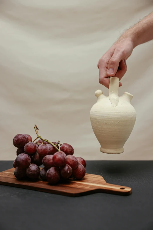 a hand holding a vase over gs that are still on a  board