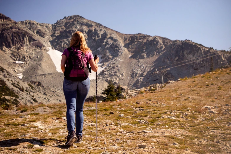 a woman is hiking down the side of a mountain