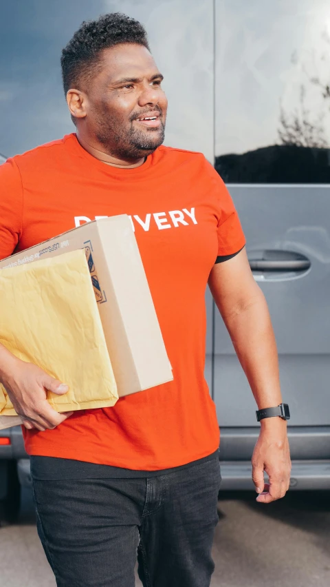 a man in an orange shirt carrying two boxes