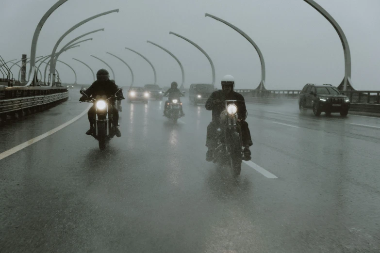 motorcycles riding down a wet road in heavy rain