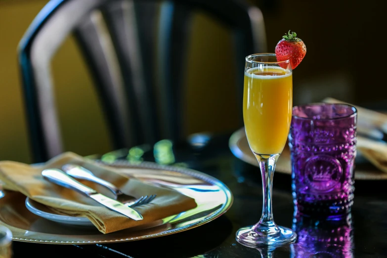 a table setting with a glass and orange and strawberry drink