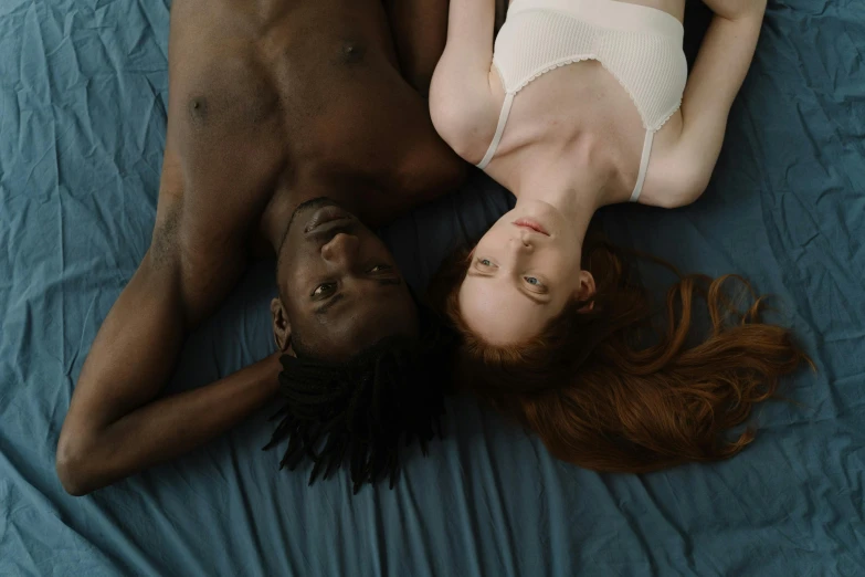 an african american man and a red headed woman laying on top of each other