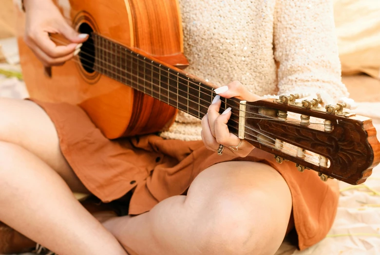 a woman holding an acoustic guitar is sitting