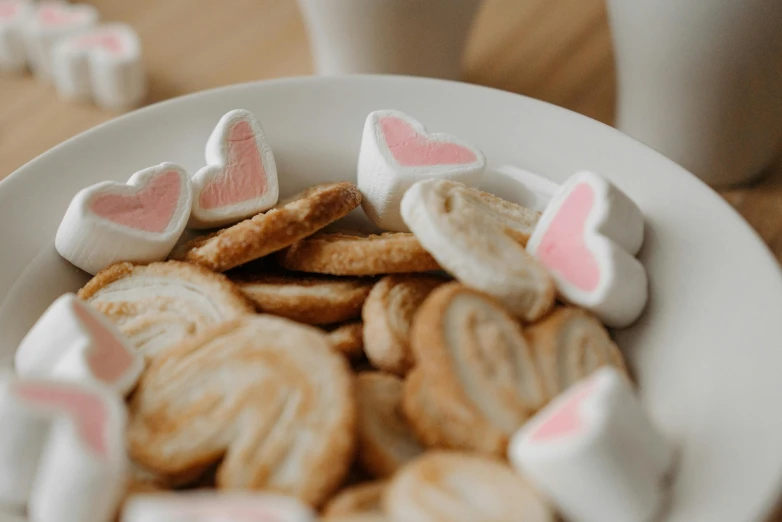 white bowl of cookies with pink hearts on them