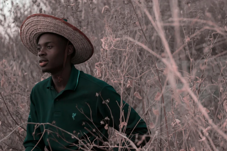 a man standing in the tall grass in a straw hat