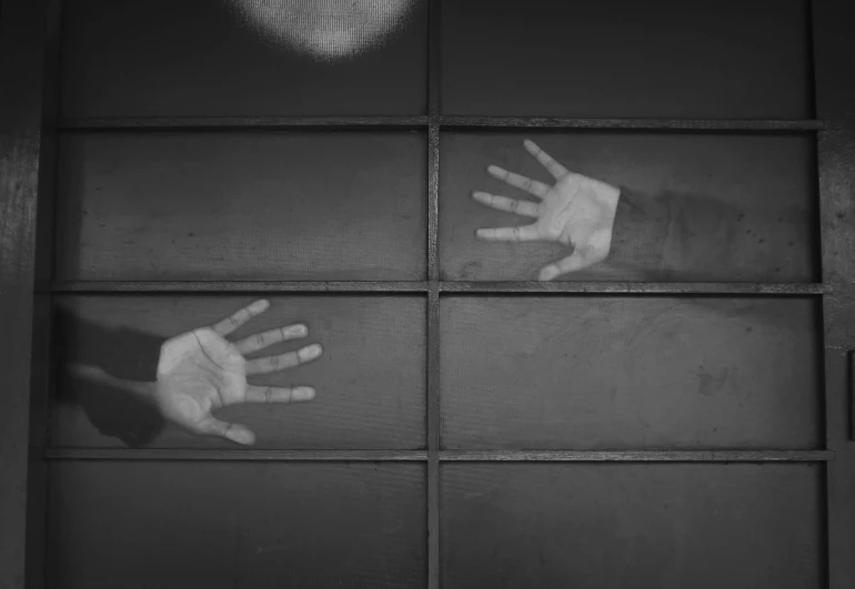 two hands reaching out of a closed window