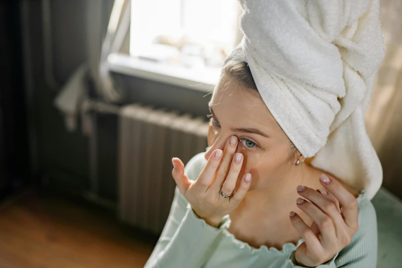 a young woman covers her eyes with a towel