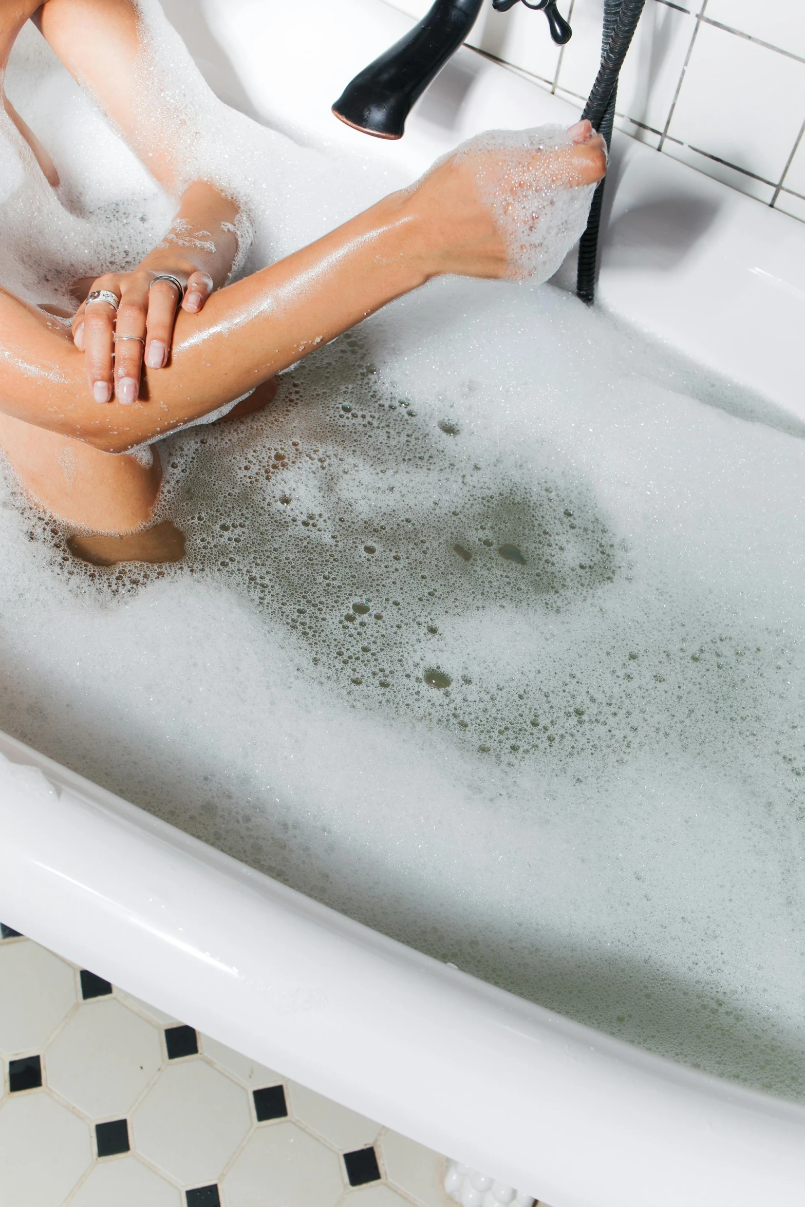 a girl in high heels laying in a tub full of bubbles of water