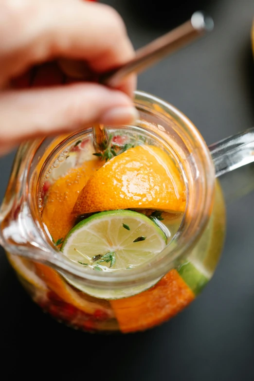 a person is putting oranges and limes in their mason jar