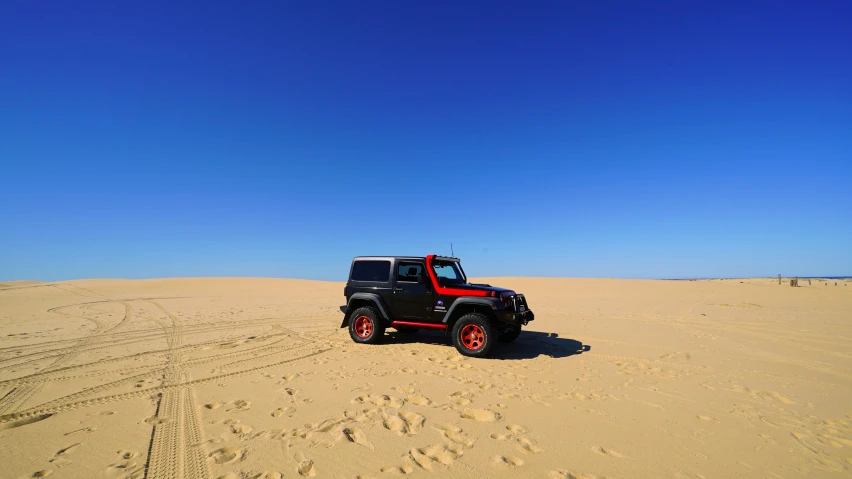 there is a vehicle driving on the sand