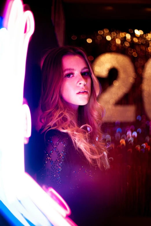 a woman is standing in front of a neon sign