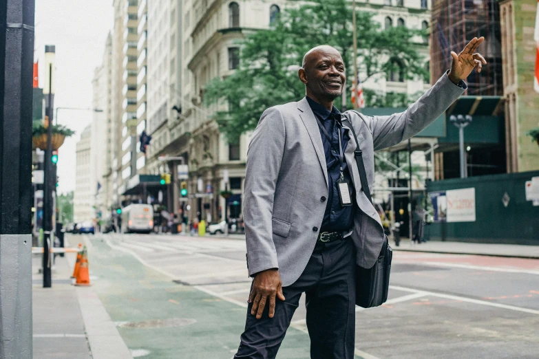 a man stands on a city street waving