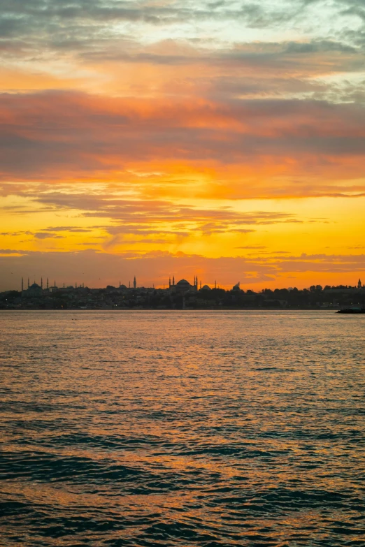 some buildings are silhouetted against a yellow, orange, and black sky