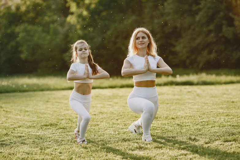two women in white outfits, one wearing a , are in the grass and another has both arms in their pockets