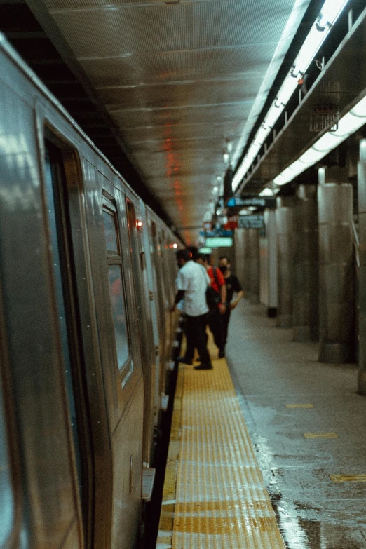 people stand on the platform as the train pulls up to the station