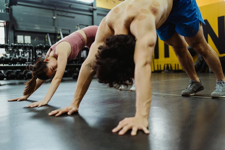 two people in a gym with their hands together on one foot