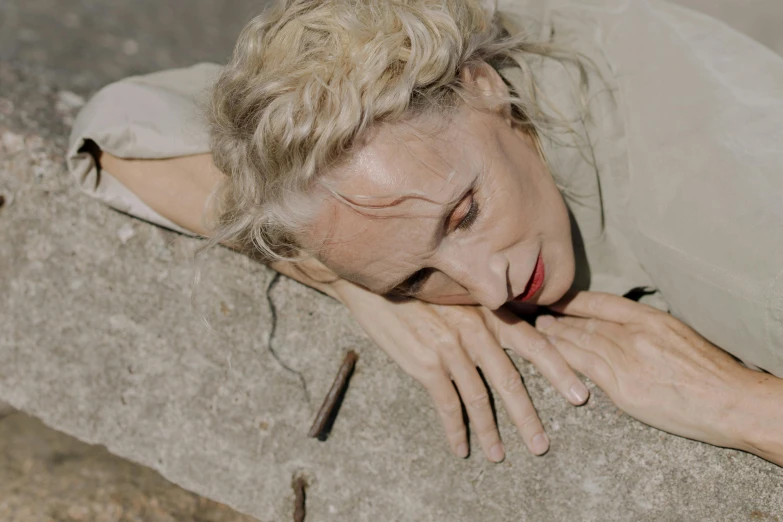 a woman laying down in the sand with her hand on the ground