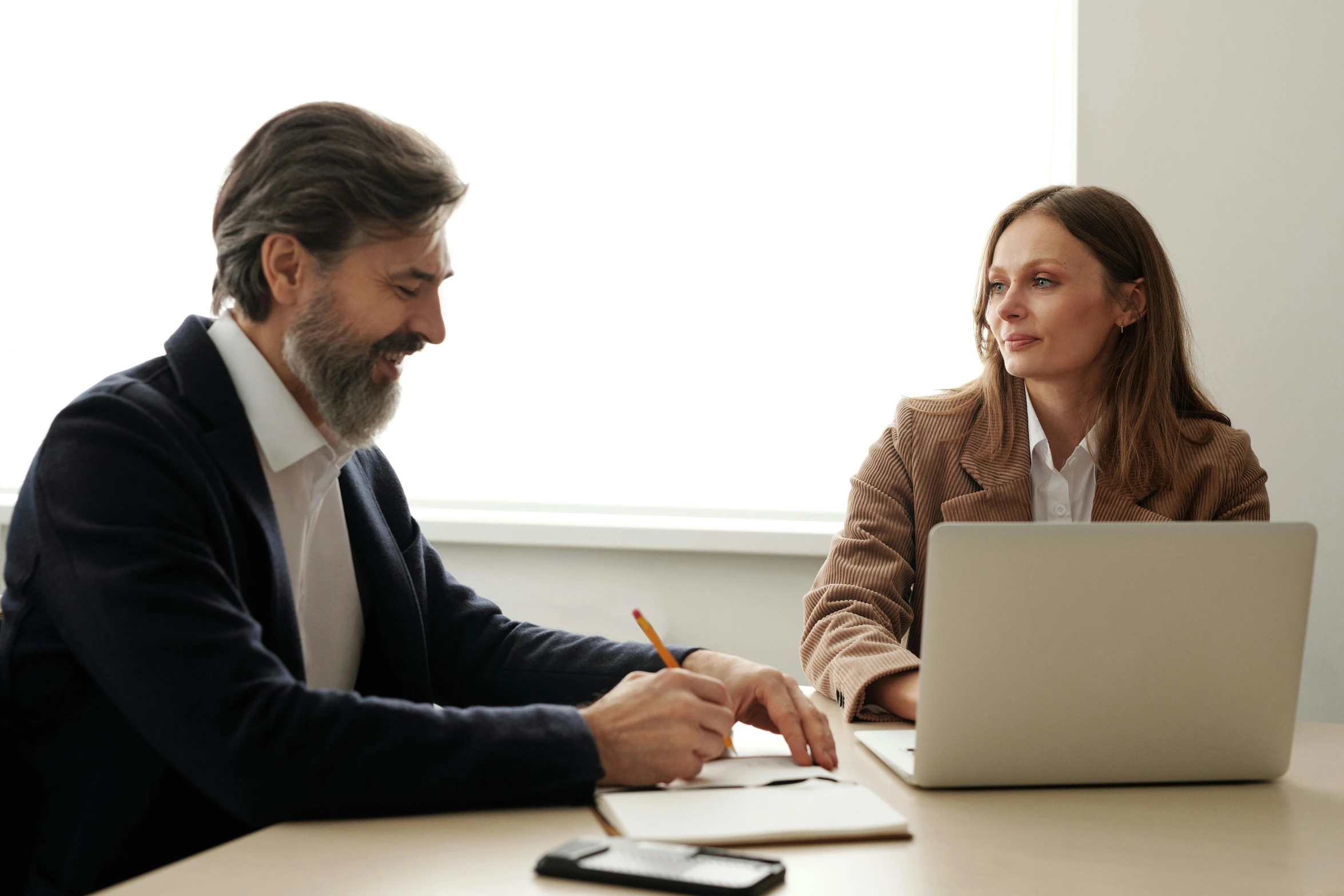 a man in a business suit sitting down while working on a laptop