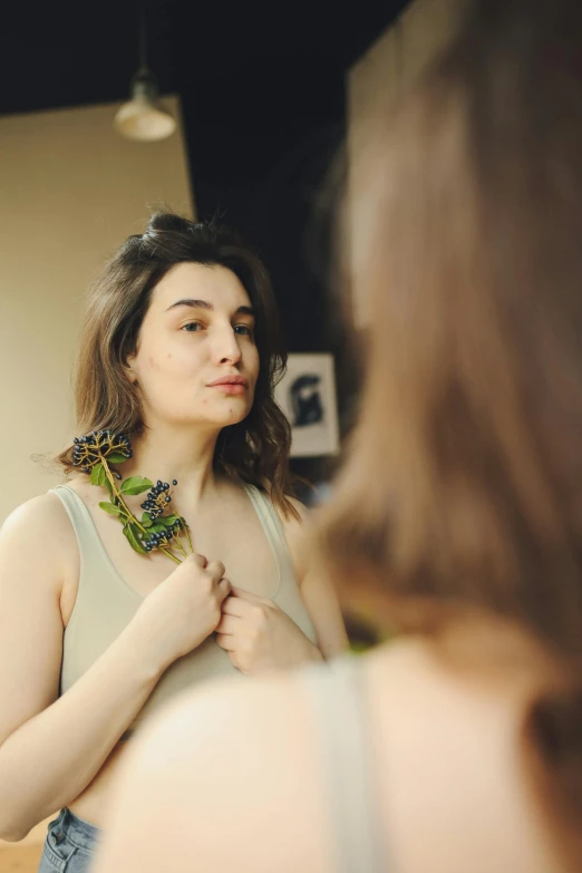 a woman fixing her jewelry on while looking into a mirror