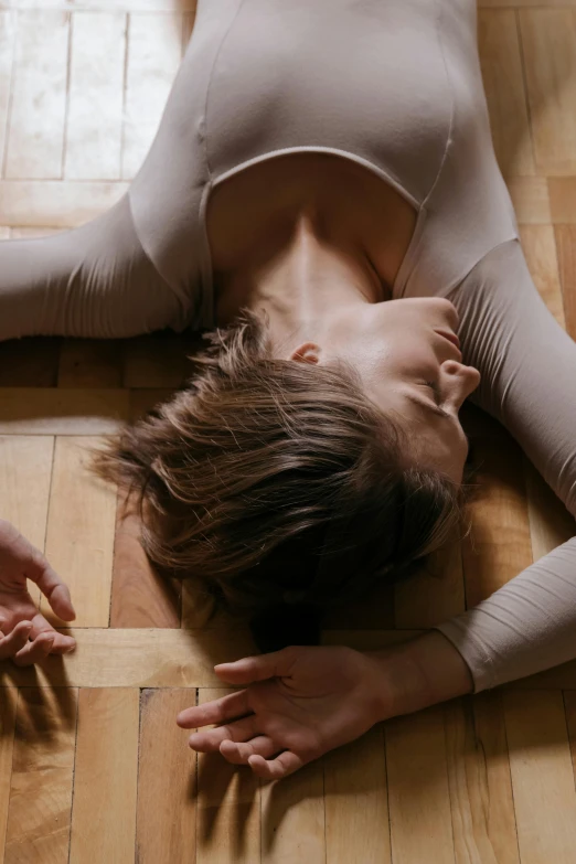 a women who is laying down on the floor and her hands are over her head