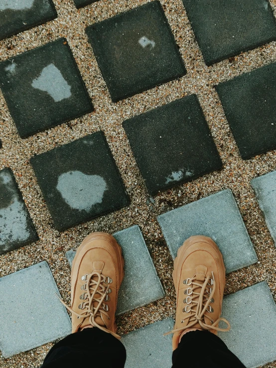 someone in brown sneakers stands on pavement