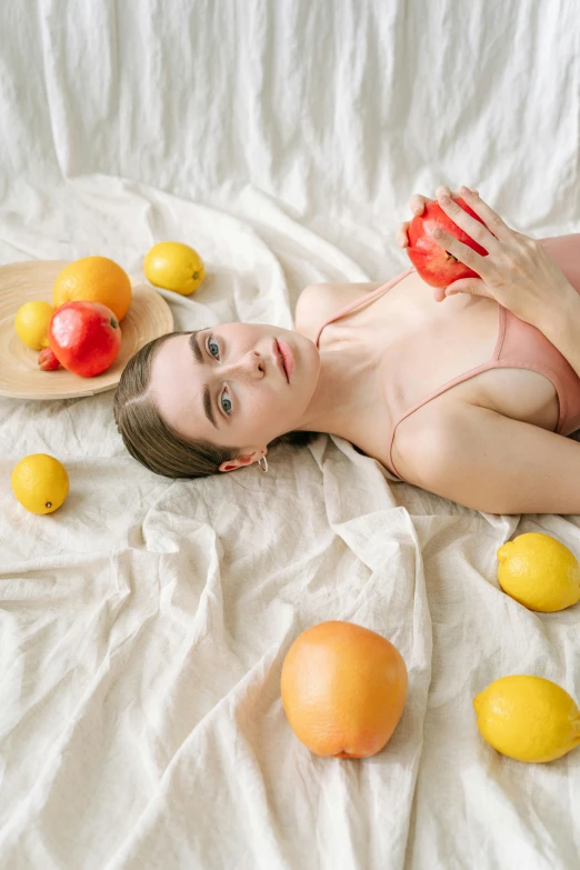 a  woman in a bikini lies on the bed next to fruit