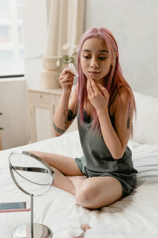 a  is on the bed using a make up mirror