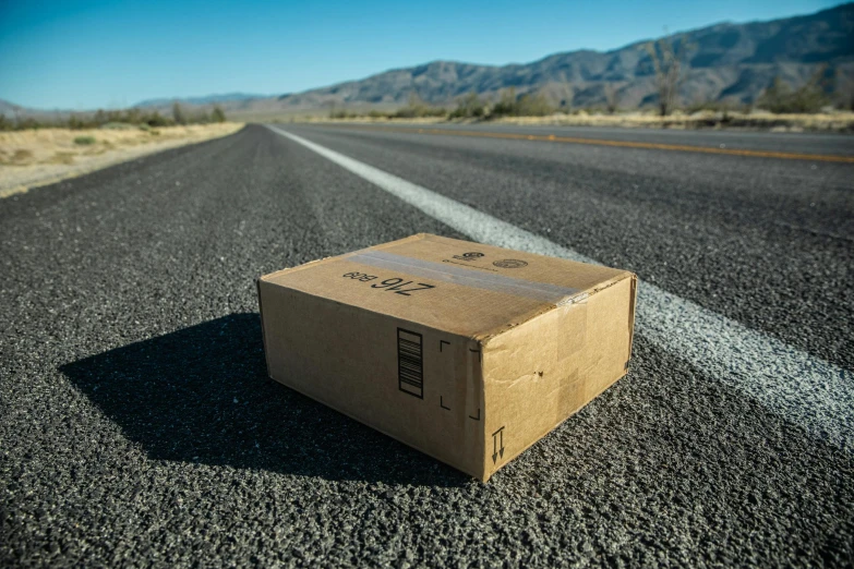 a cardboard box on the road that is missing its handle