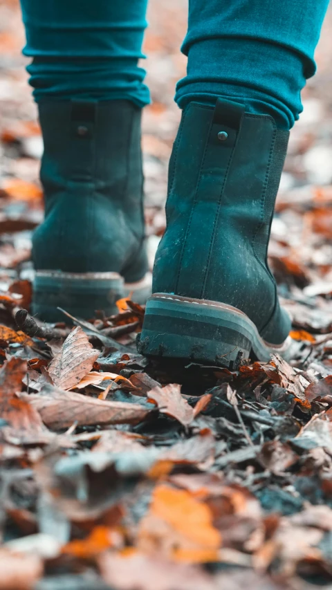 a person's boots on a pile of leaf