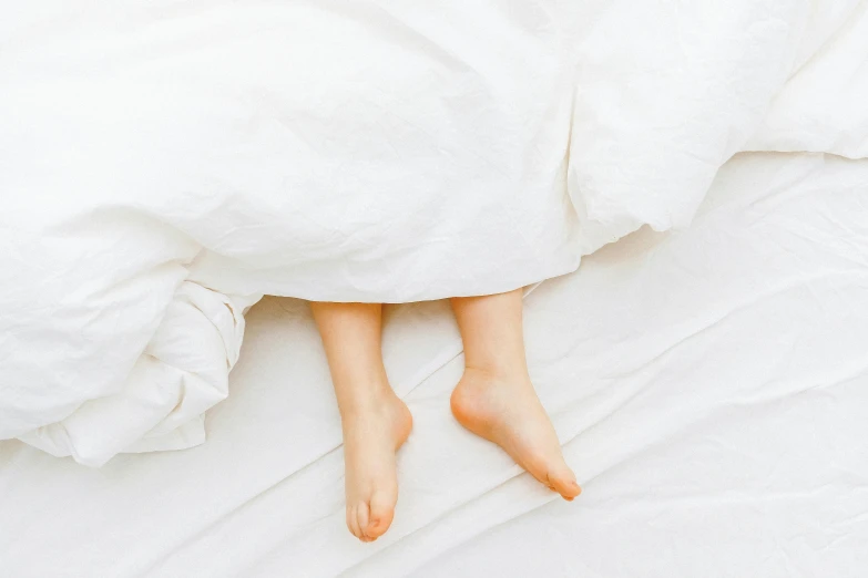 a persons feet laying under the covers of a bed