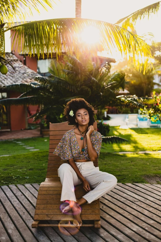 a young woman in white jeans, wearing a shirt and sitting on a wooden bench