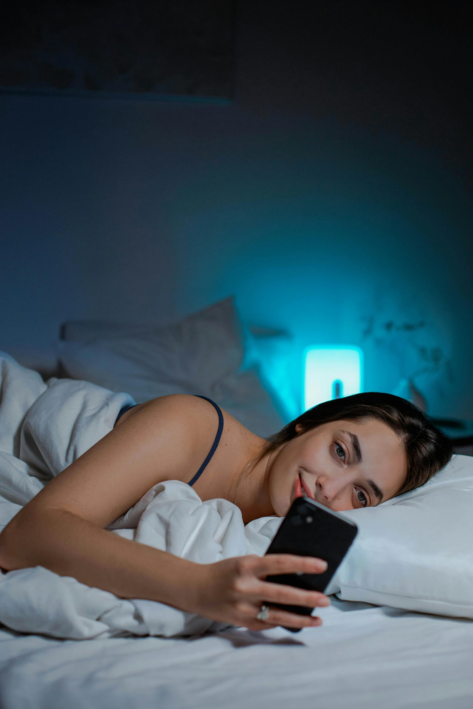 there is a woman lying on her bed looking at her cellphone