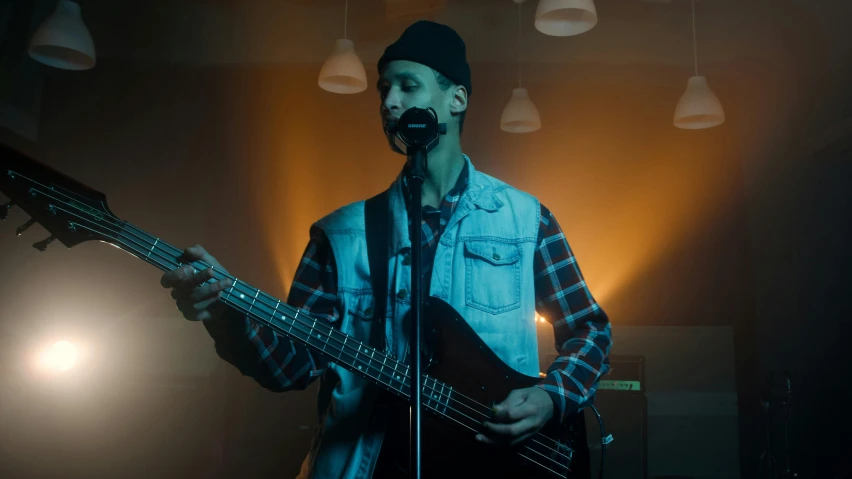 a man with a hat holding a guitar on stage