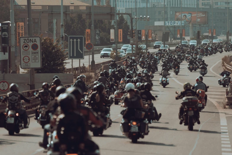 large group of bikers driving down the street in traffic