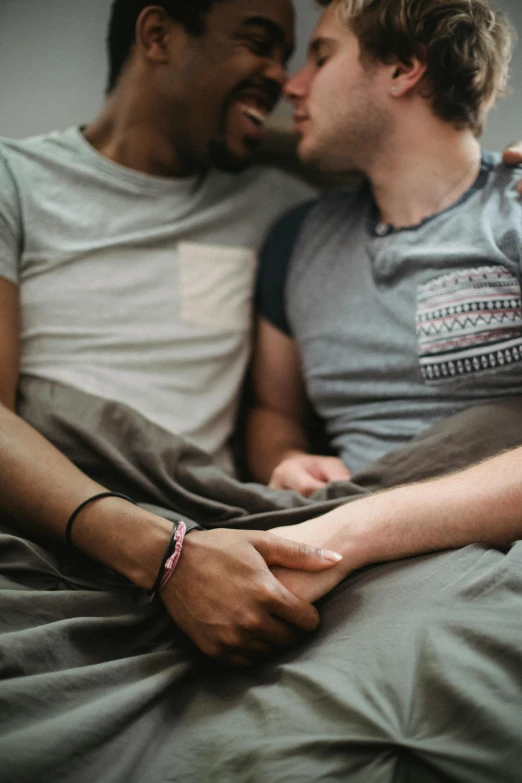 two men laying on the bed kissing each other