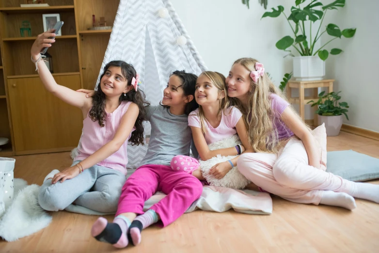 five girls sitting on the floor taking pictures