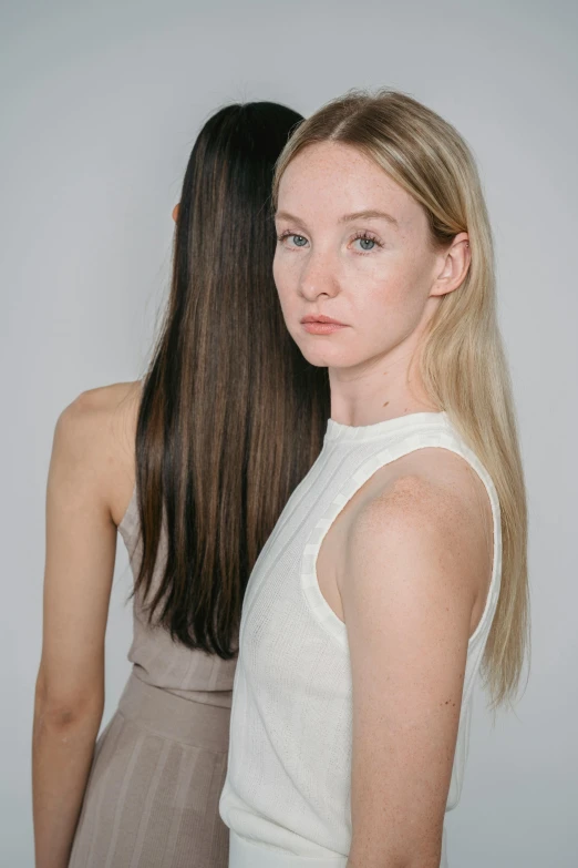 two woman looking to their left, one with long hair