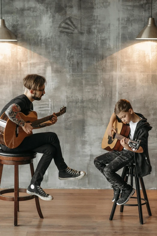 two young men sitting and playing instruments in a room