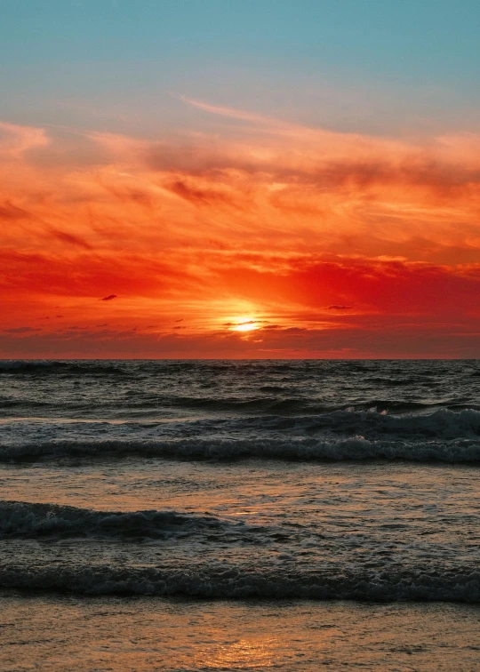 the sun setting at sea with orange and blue skies