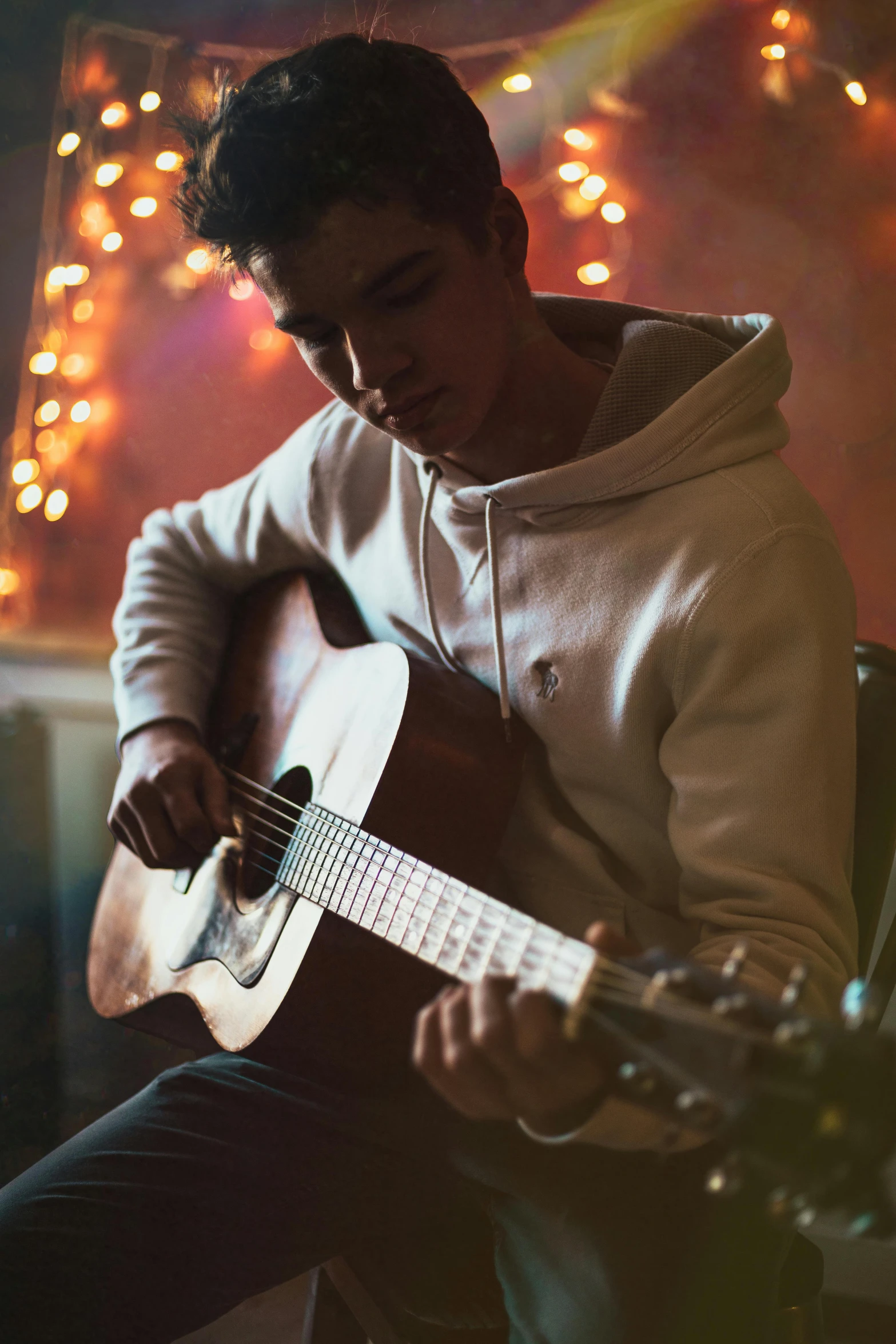 a man sitting on top of a chair while playing a guitar