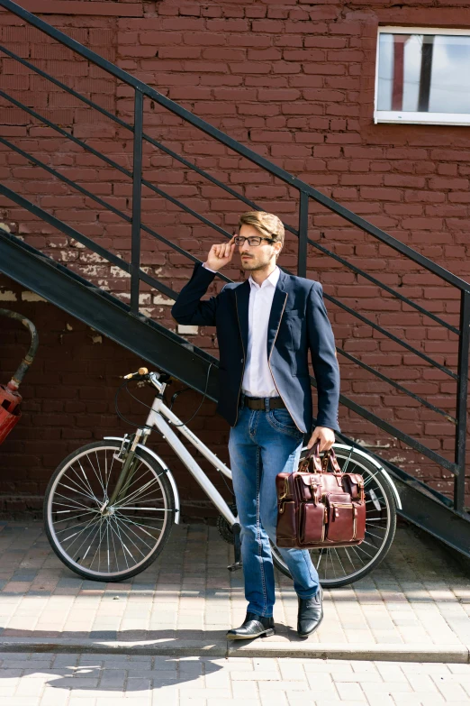 a man wearing glasses and carrying luggage stands in front of a stair railing