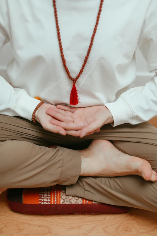 a person sitting in the middle of a wooden floor with their hands together