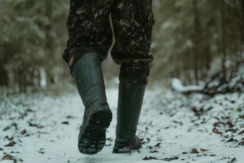 a person walking in the snow with dark boots and well - loved boots