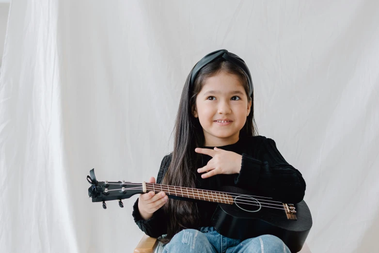 a girl sitting down and holding a guitar