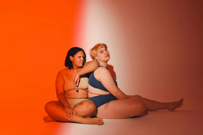 two beautiful women sitting on the ground with one holding the other