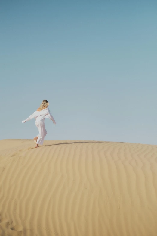 the woman in white is walking on the desert