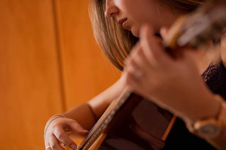 a woman holds an instrument while looking down at the strings