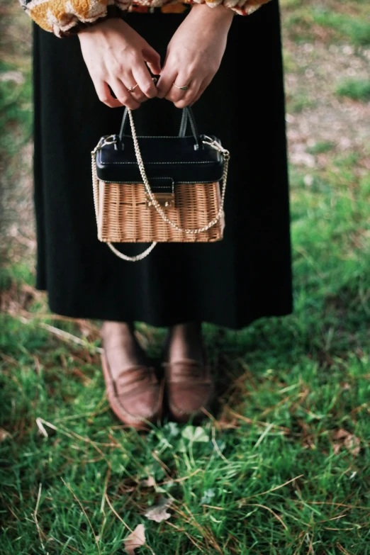 the woman is holding a small basket purse