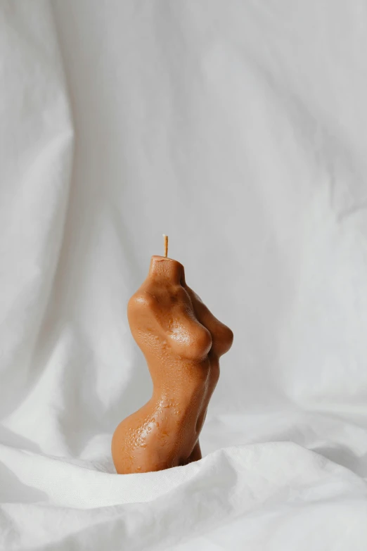 an orange ceramic female body sculpture against a white background